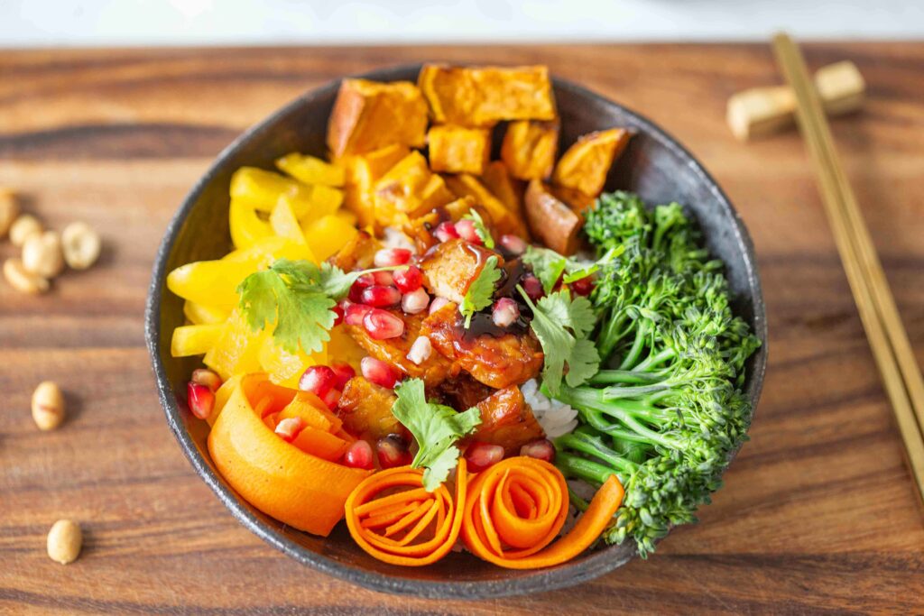 Värikäs vegaaninen kulhoruoka, jossa rapeaa tempeä, paprikaa, porkkanaa ja parsakaalia.