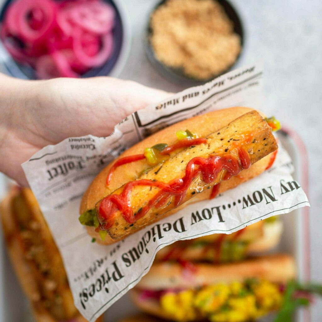 Vegaaninen hot dog paperikääreessä kädessä.