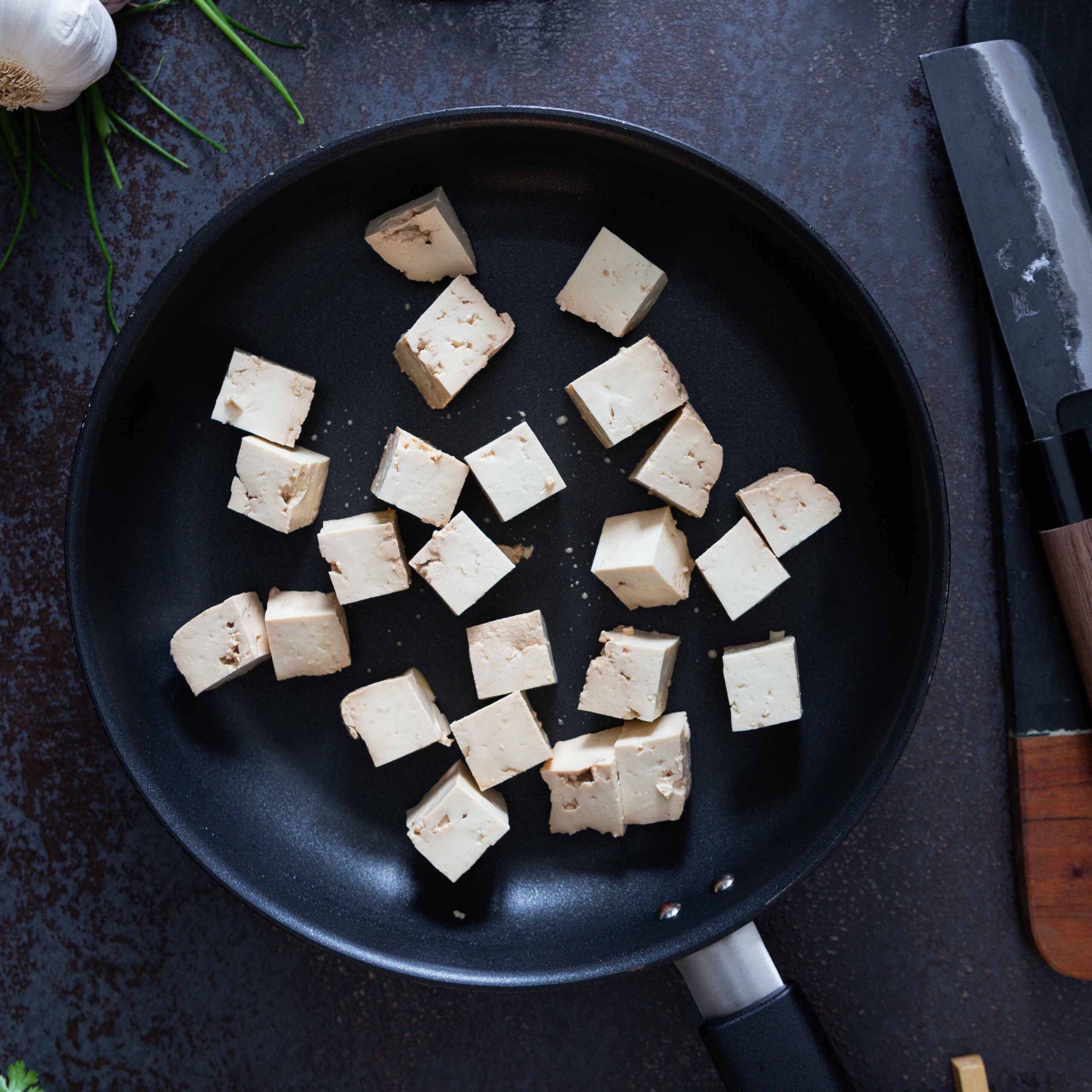 Tofun paistaminen aloitetaan kuutioimalla tofu ja nakkaamalla se pannulle.
