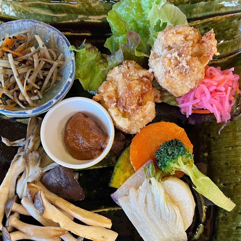 Japanilainen kasvisruoka-annos lähikuvassa: tempuraa, pikkeleitä ja kasviksia ja sieniä.