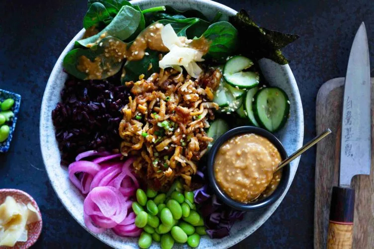 Värikäs sushi bowl eli sushikulho, jonka pohjalla on riisiä ja päällä kurkkua, edamamepapuja, marinoitua punasipulia ja rapeaksi paahdettua tofua sekä seesamikastiketta.