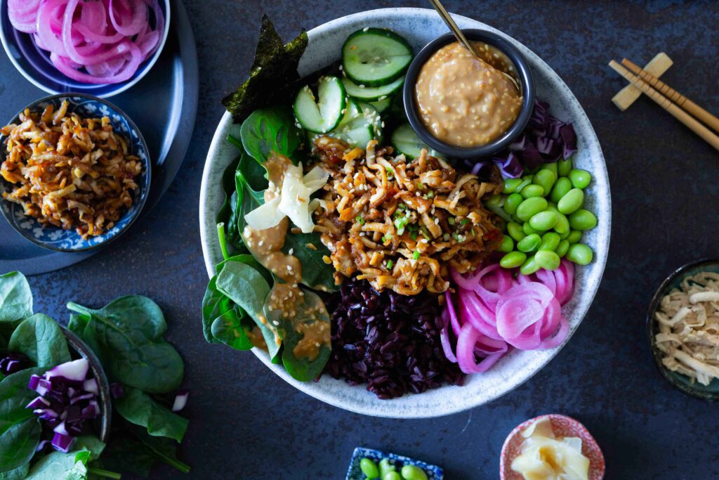 Värikäs sushi bowl eli sushikulho, jonka pohjalla on riisiä ja päällä kurkkua, edamamepapuja, marinoitua punasipulia ja rapeaksi paahdettua tofua sekä seesamikastiketta.