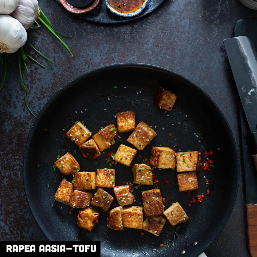 Rapeita Aasia-tofu kuutioita paistinpannulla ruohosipulin, chilin ja seesaminsiementen kera.