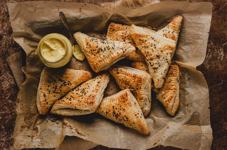 Tofulla täytetyt, kolmionmalliset sienipasteijat uunipellillä uunista juuri otettuina.