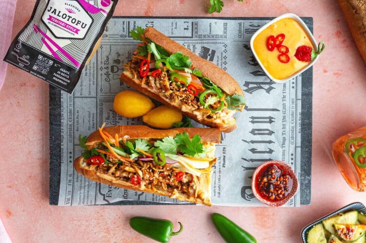 Rapealla teriyakitofulla, kasviksilla ja majoneesilla täytetyt banh mi patongit paperin päällä, vierellä Jalotofu teriyaki.