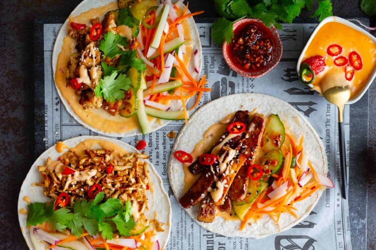 Värikkäät banh mi tortillat avonaisina pöydällä majoneesin kera.